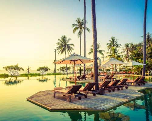 An exclusive, low-density private villa infinity pool overlooking a secluded ocean cove during sunset